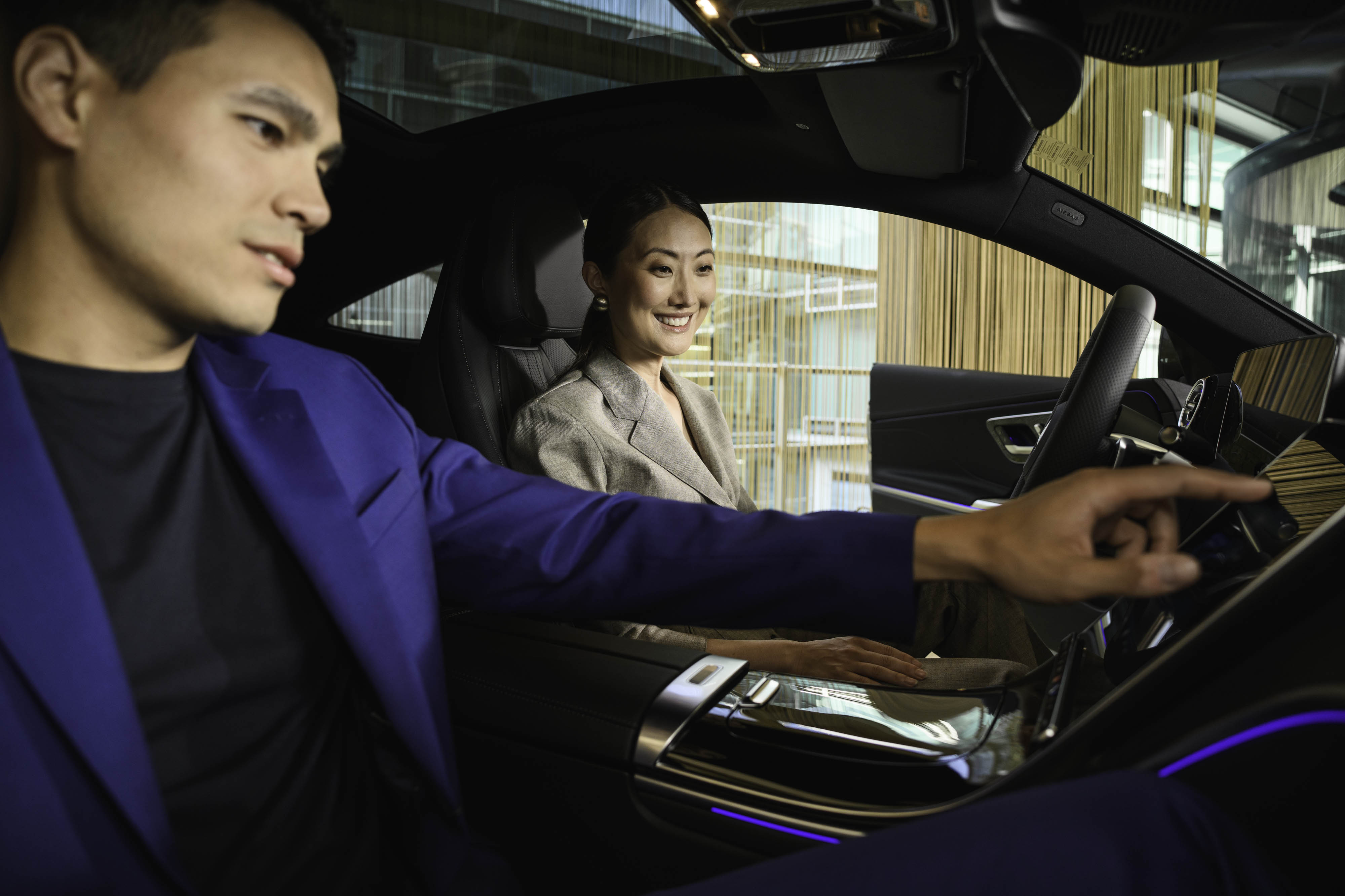 Soluções de Financiamento e Mobilidade Mercedes-Benz. Duas pessoas dentro de um Mercedes-Benz, a mexer no painel de control.