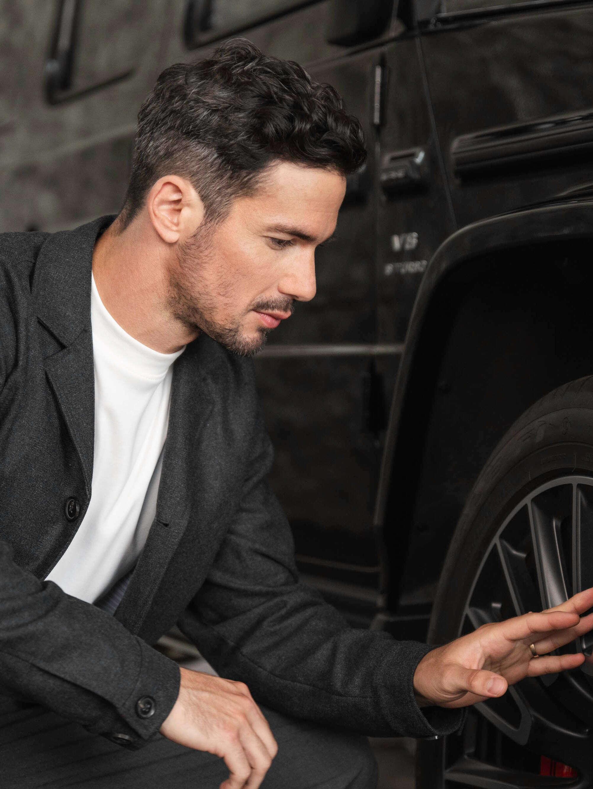 Uma pessoa agachada a mexer na roda de um Mercedes-Benz.