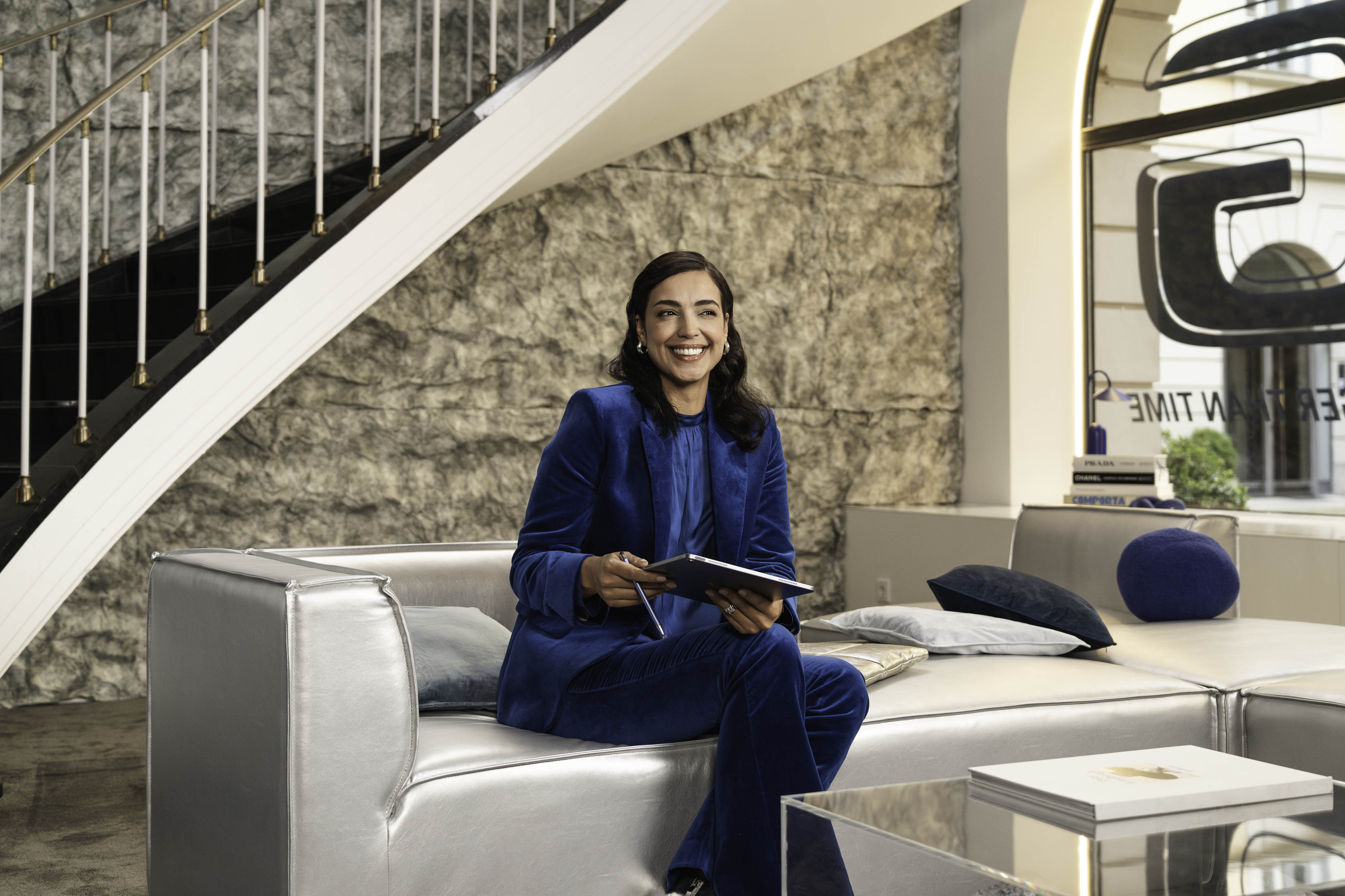 Uma pessoa num sofa com um tablet na mão, a sorrir. Portal do Cliente Mercedes-Benz