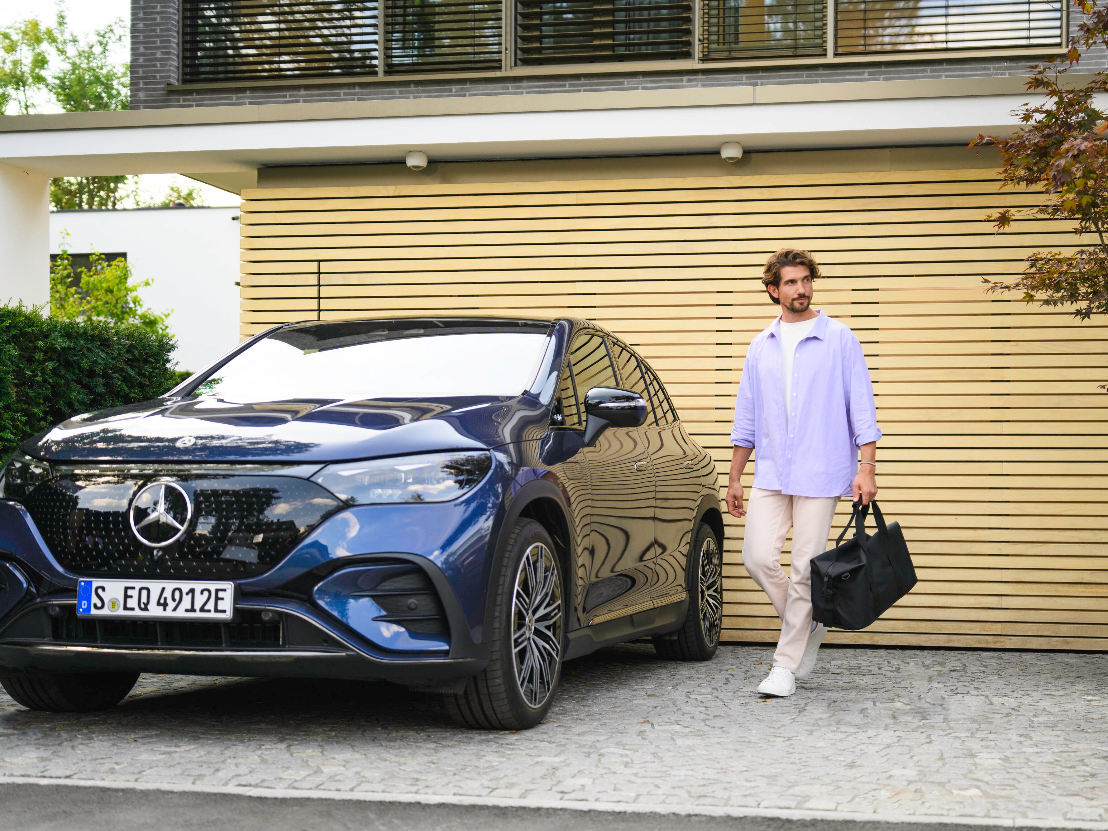 Uma pessoa a caminhar até ao seu Mercedes-Benz com um saco na mão.