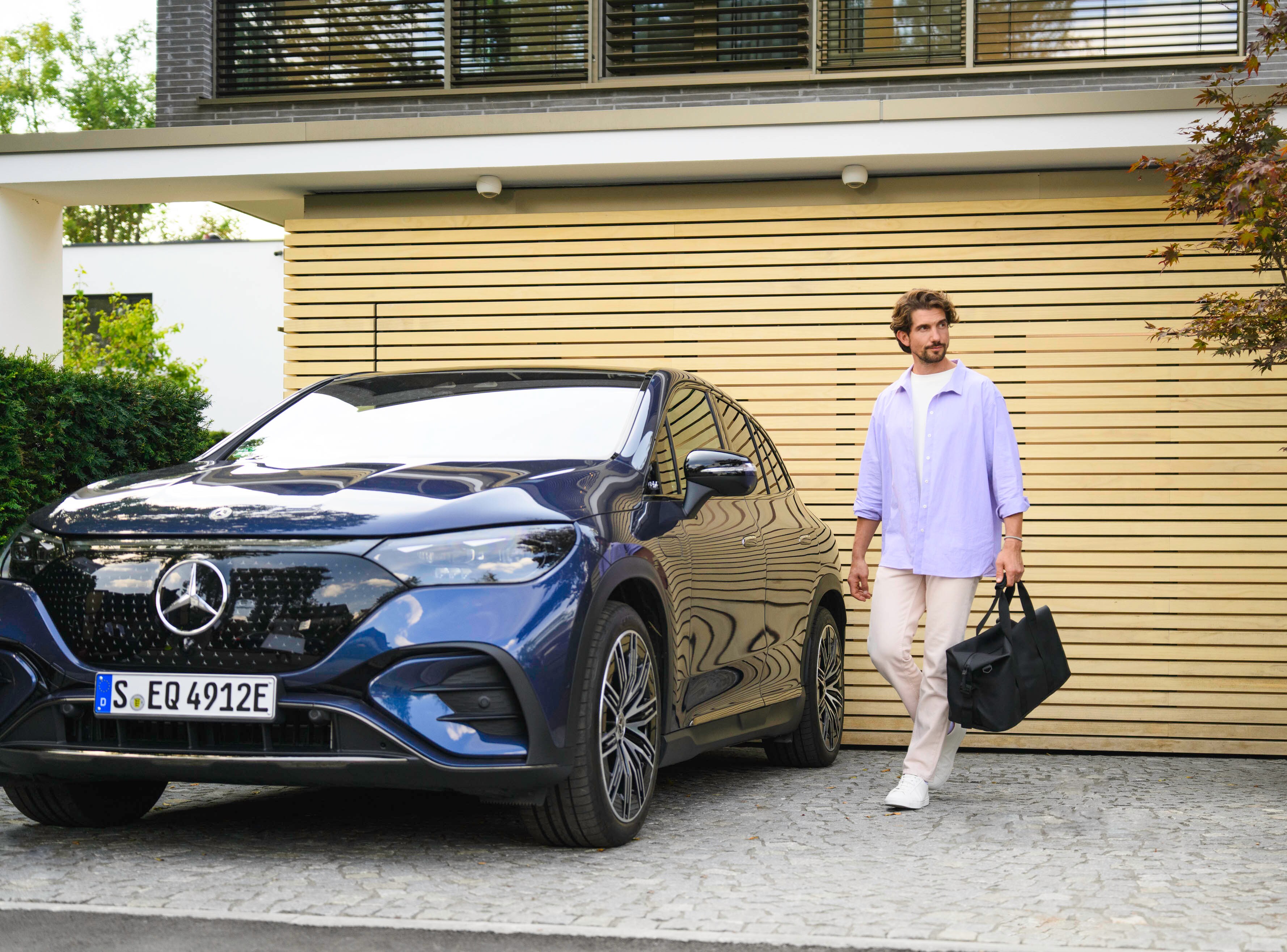 Uma pessoa a caminhar até ao seu Mercedes-Benz com um saco na mão.